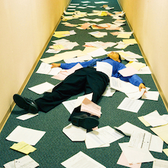 Businessman stressed laying down on floor with documents.